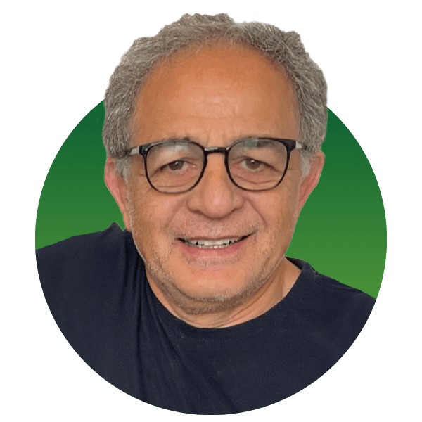 A smiling older person with glasses and gray hair is wearing a dark shirt. The background is a gradient of green.